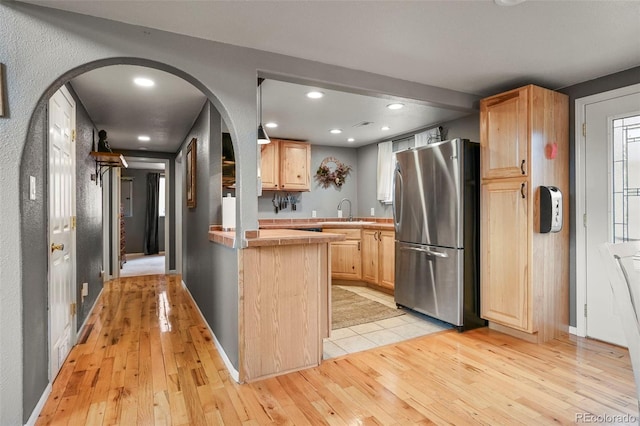 kitchen with light hardwood / wood-style flooring, sink, stainless steel fridge, and light brown cabinets