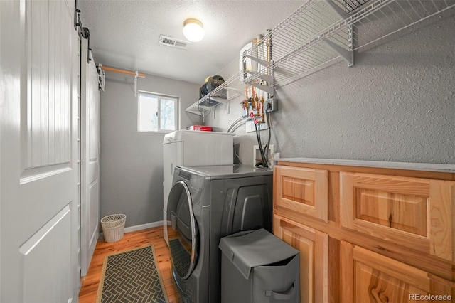 washroom with separate washer and dryer, light hardwood / wood-style flooring, and a textured ceiling