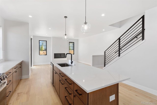 kitchen with light hardwood / wood-style floors, a center island, sink, stainless steel appliances, and decorative light fixtures