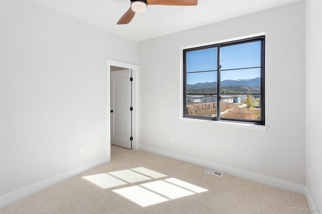 carpeted spare room with ceiling fan and a mountain view