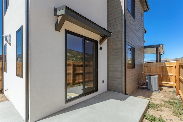 view of exterior entry featuring central AC and a patio area