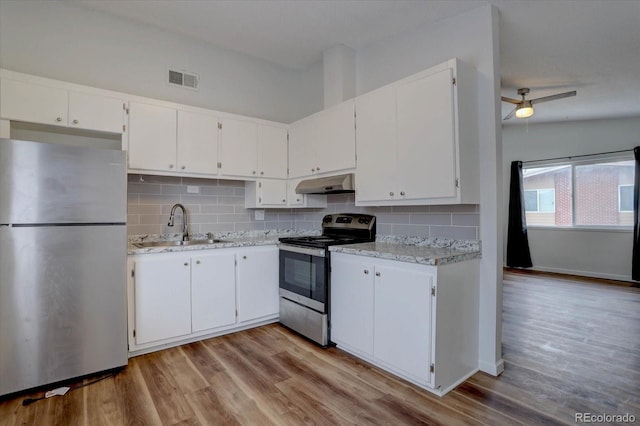2938 Eliot Cir, Westminster, CO 80030 - kitchen with appliances with stainless steel finishes, under cabinet range hood, a sink, tasteful backsplash, and white cabinetry