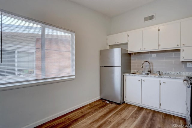 2938 Eliot Cir, Westminster, CO 80030 - kitchen with freestanding refrigerator, a sink, decorative backsplash, white cabinetry, and light wood-type flooring