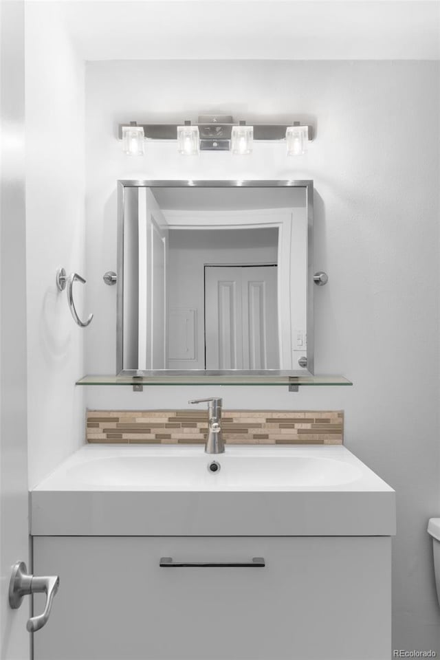 bathroom featuring toilet, vanity, and decorative backsplash