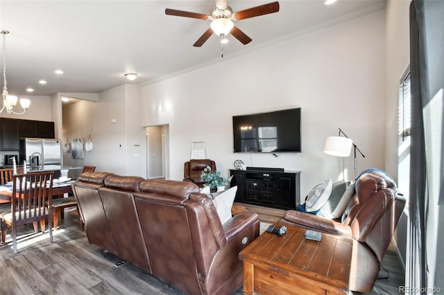 living room with wood-type flooring and ceiling fan with notable chandelier