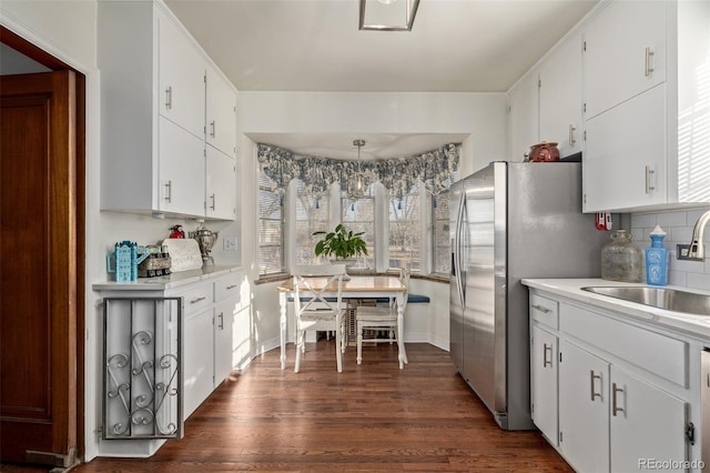 kitchen featuring sink, white cabinetry, dark hardwood / wood-style floors, pendant lighting, and backsplash