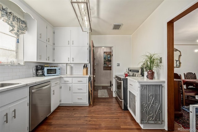 kitchen with white cabinetry, appliances with stainless steel finishes, dark wood-type flooring, and backsplash