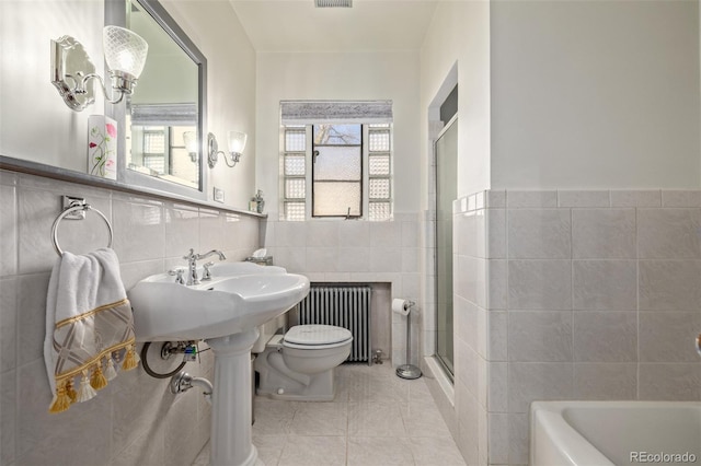 bathroom featuring radiator, tile walls, tile patterned floors, independent shower and bath, and toilet