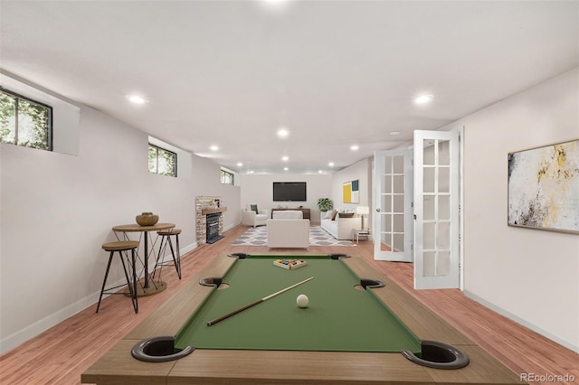 recreation room featuring french doors, hardwood / wood-style floors, a fireplace, and billiards