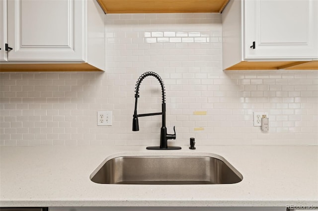 470 Bear Creek Rd, Colorado Springs, CO 80906 - kitchen view of decorative backsplash, a sink, white cabinets, and light stone counters