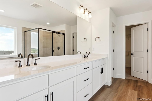 8346 Cokedale Cir, Littleton, CO 80125 - bathroom with double vanity, a shower stall, wood finished floors, a walk in closet, and recessed lighting