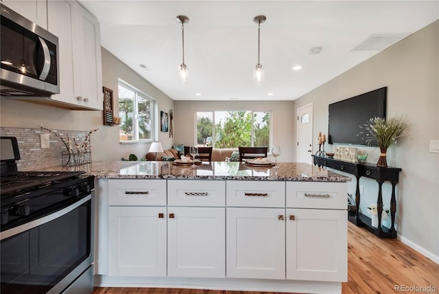 6245 W 53rd Ave, Arvada, CO 80002 - kitchen with stainless steel appliances, a peninsula, light stone countertops, healthy amount of natural light, and recessed lighting