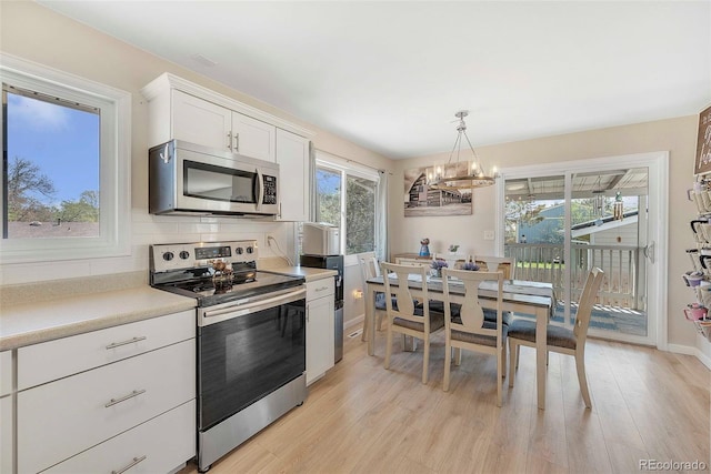 3516 Marigold St, Evans, CO 80620 - kitchen with stainless steel appliances, a notable chandelier, white cabinetry, and light wood finished floors