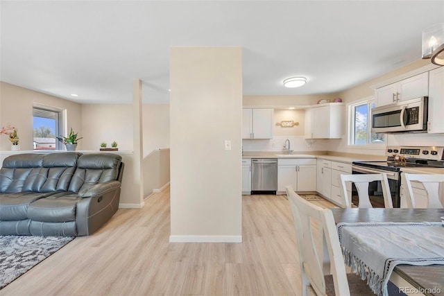 3516 Marigold St, Evans, CO 80620 - kitchen featuring appliances with stainless steel finishes, light countertops, light wood-style flooring, white cabinetry, and open floor plan