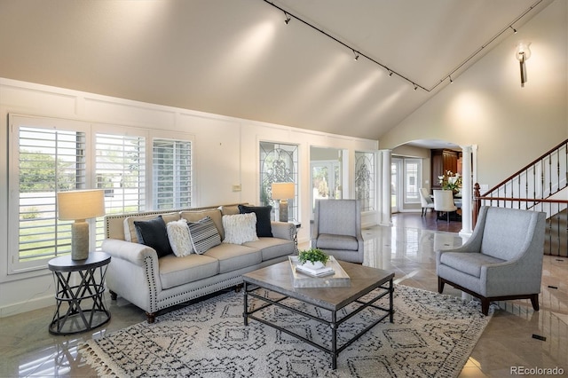 living room featuring decorative columns, rail lighting, light tile patterned floors, and high vaulted ceiling