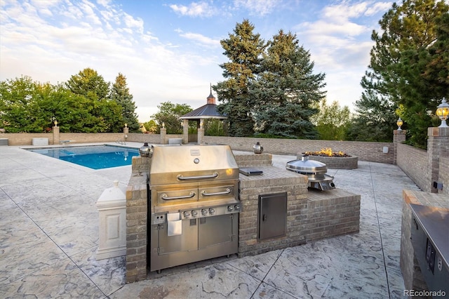 view of patio featuring area for grilling, a grill, and a fire pit