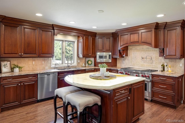 kitchen with sink, stainless steel appliances, wood-type flooring, a kitchen island, and decorative backsplash