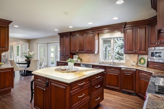 kitchen featuring dark wood-type flooring, sink, tasteful backsplash, stainless steel microwave, and a kitchen island