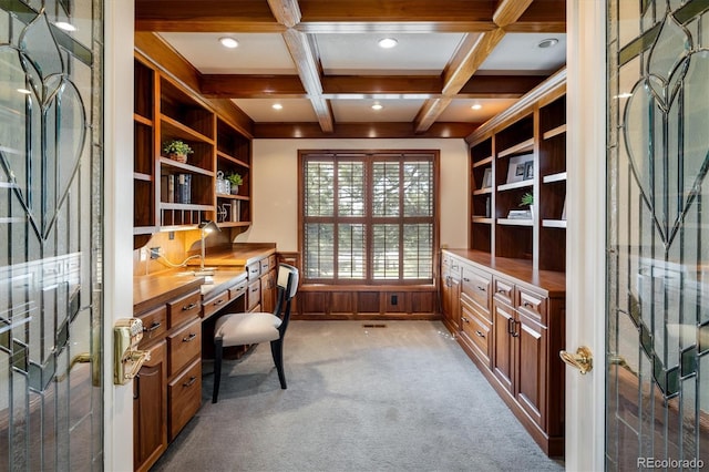 office featuring built in shelves, coffered ceiling, built in desk, beamed ceiling, and light colored carpet