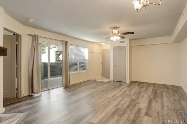 spare room featuring ceiling fan with notable chandelier and light wood-type flooring