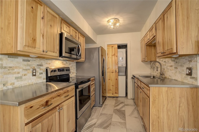 kitchen with stacked washing maching and dryer, stainless steel countertops, appliances with stainless steel finishes, and a sink