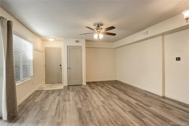 empty room featuring light wood-style flooring, visible vents, ceiling fan, and baseboards