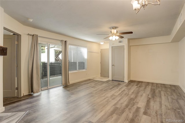 unfurnished room featuring light wood finished floors, ceiling fan with notable chandelier, baseboards, and visible vents