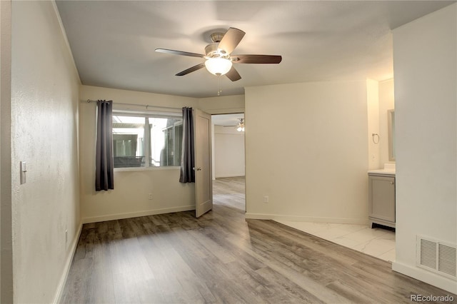 unfurnished room featuring light wood finished floors, visible vents, baseboards, and ceiling fan