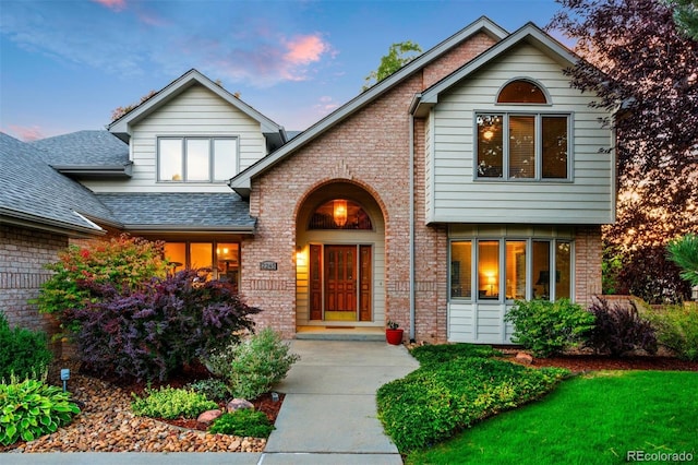 view of front of home featuring brick siding and a shingled roof