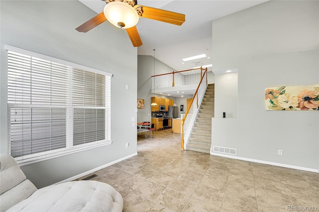 14333 E Napa Pl Unit 5D, Aurora, CO 80014 - living area with high vaulted ceiling, stairs, baseboards, a ceiling fan, and a skylight