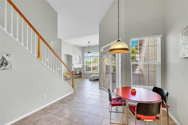 14333 E Napa Pl Unit 5D, Aurora, CO 80014 - dining space featuring a towering ceiling, a ceiling fan, a glass covered fireplace, baseboards, and light tile patterned floors