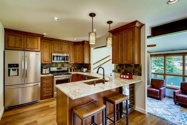 68 Golf Course Dr Unit 11, Copper Mountain, CO 80443 - kitchen with appliances with stainless steel finishes, a sink, a peninsula, light wood-style floors, and decorative backsplash