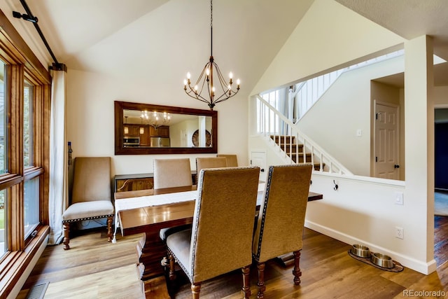 68 Golf Course Dr Unit 11, Copper Mountain, CO 80443 - dining space featuring wood finished floors, a chandelier, baseboards, high vaulted ceiling, and stairs