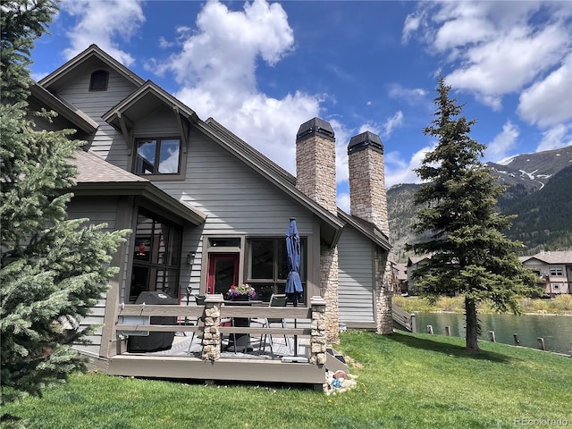 68 Golf Course Dr Unit 11, Copper Mountain, CO 80443 - back of house featuring a chimney, a deck with mountain view, and a lawn