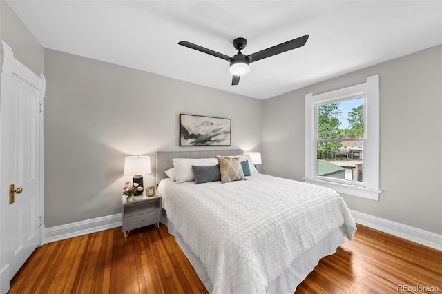 bedroom with baseboards, hardwood / wood-style floors, and a ceiling fan