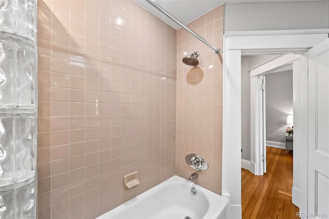 bathroom featuring bathing tub / shower combination, wood finished floors, and baseboards