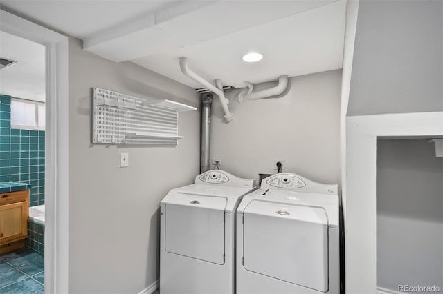laundry room featuring washer and dryer and dark tile patterned flooring