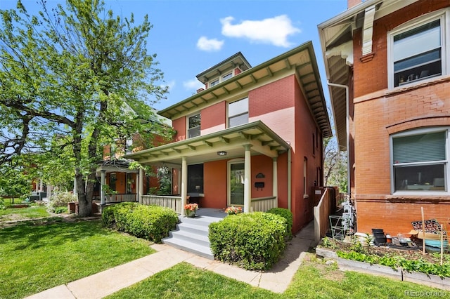 view of front of home featuring covered porch, a front yard, and brick siding