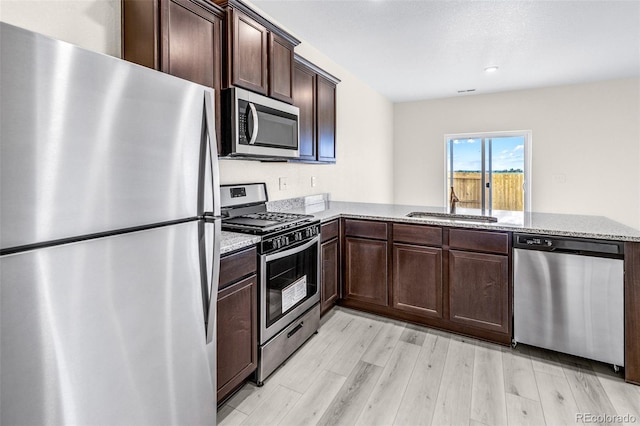 kitchen with kitchen peninsula, appliances with stainless steel finishes, light hardwood / wood-style flooring, dark brown cabinetry, and sink