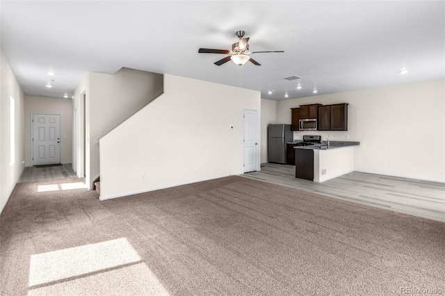 unfurnished living room featuring ceiling fan and light carpet