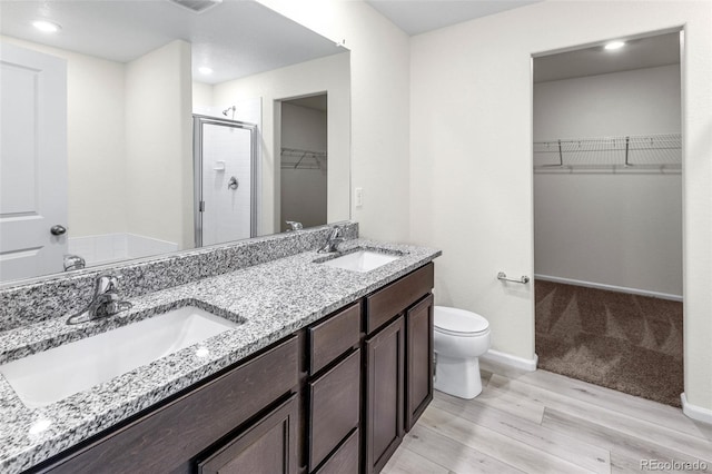 bathroom featuring a shower stall, toilet, a sink, and wood finished floors