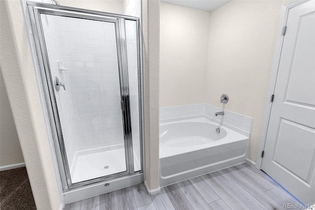 bathroom featuring a bath, a stall shower, baseboards, and wood tiled floor