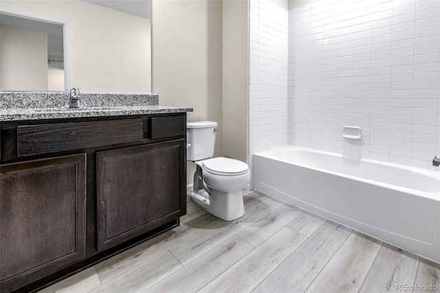 bathroom with shower / bathing tub combination, toilet, wood finished floors, and vanity