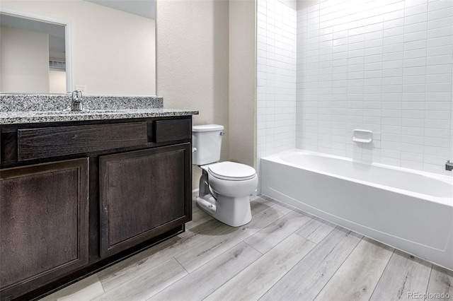 bathroom with toilet,  shower combination, vanity, and wood finished floors