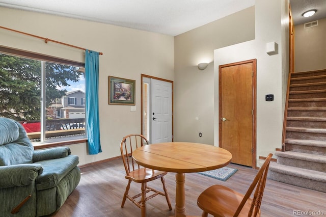 dining space featuring visible vents, baseboards, wood finished floors, and stairs