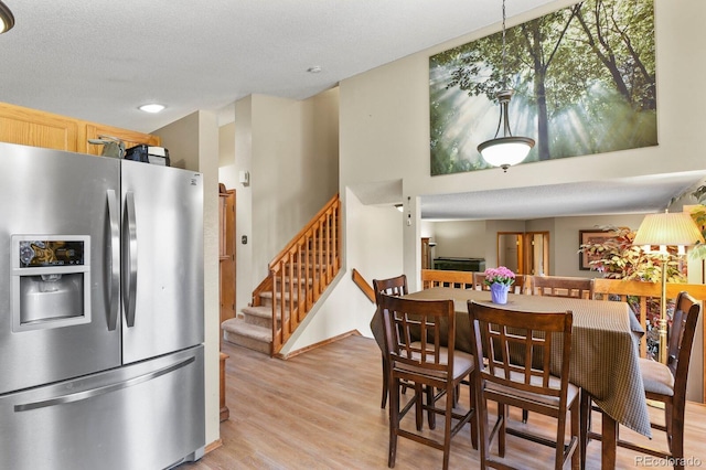 dining area with light wood finished floors, a textured ceiling, and stairs