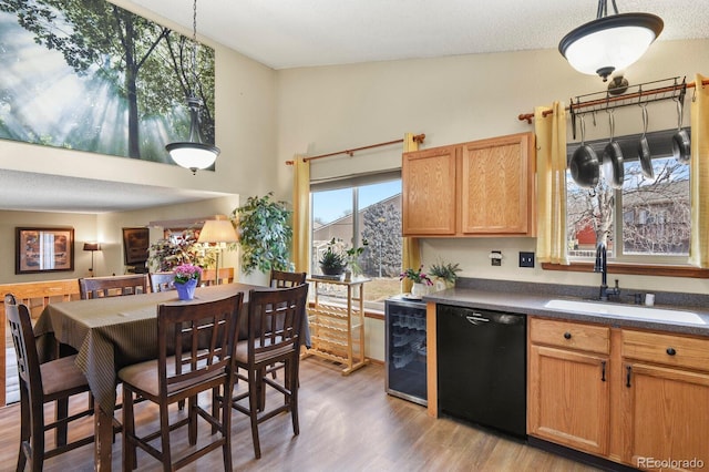 kitchen with light wood finished floors, dark countertops, wine cooler, black dishwasher, and a sink