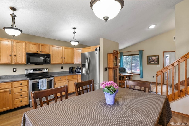 kitchen with dark countertops, light wood-type flooring, lofted ceiling, appliances with stainless steel finishes, and a textured ceiling