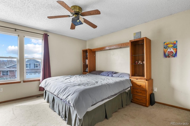 bedroom featuring light colored carpet, baseboards, and a textured ceiling