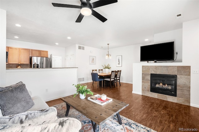 living room featuring ceiling fan, dark wood-type flooring, and a fireplace